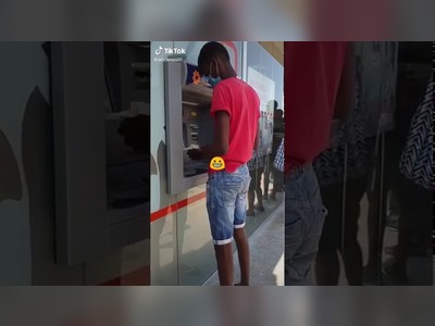 A modern banker behind a customer using ATM